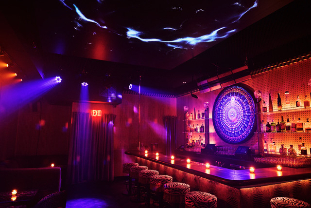 Studio’s bar under violet light, the mandala lit behind it.